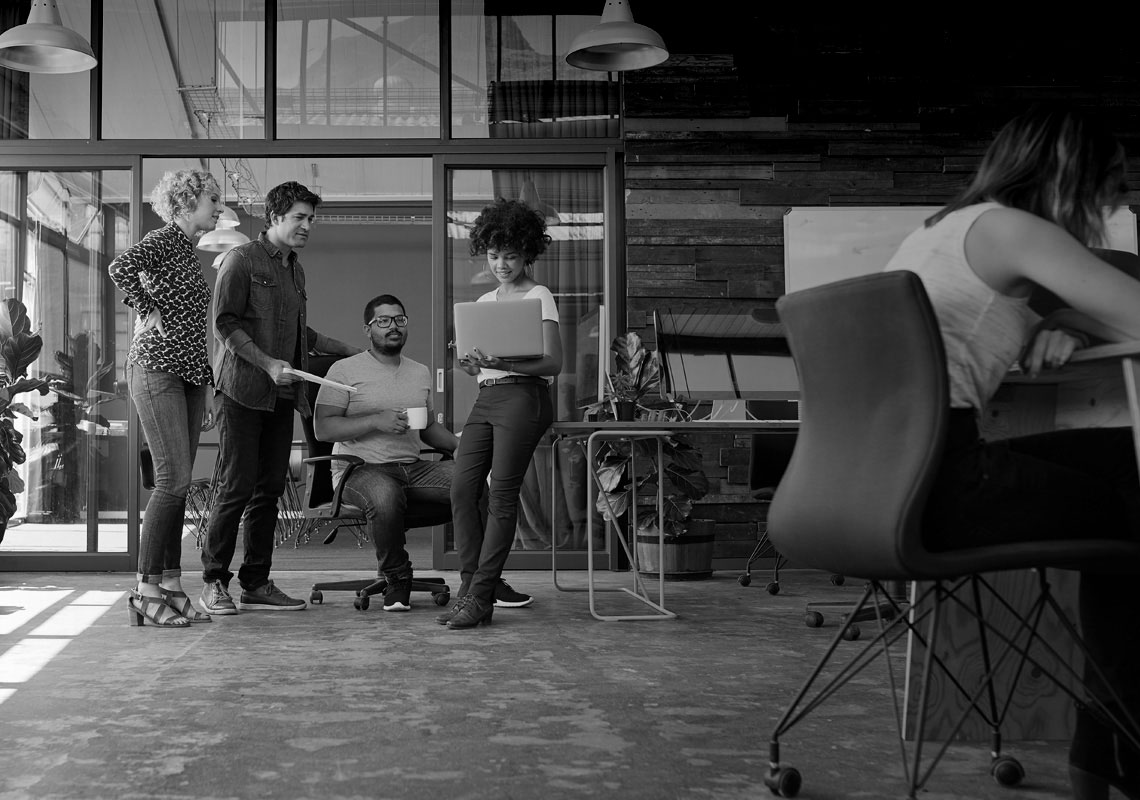 People standing in open concept office looking at computer